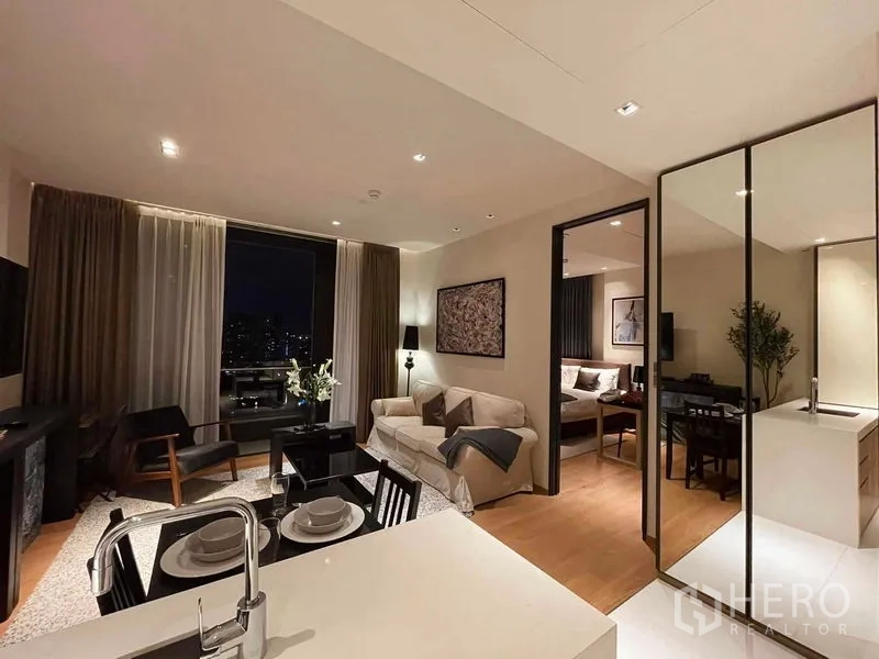 Condominium for rent in Khlong Toei, Bangkok - Open-plan living and dining area with city views through large windows and access to the bedroom.