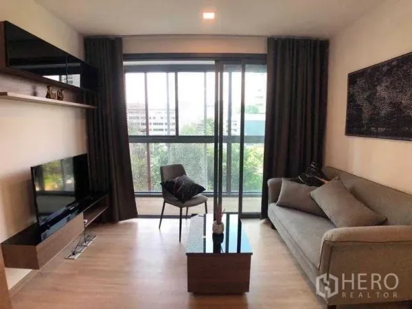 公寓 出租在Watthana, Bangkok - 采光充足的客厅，电视柜、置物架、沙发及通往阳台的推拉落地窗