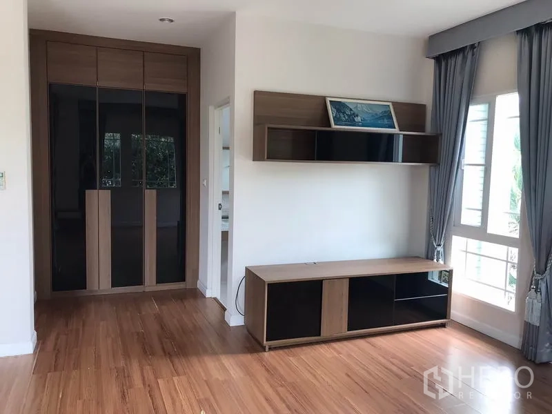 独立式住宅 出租在Khlong Sam Wa, Bangkok - 卧室一角，内置衣柜、电视柜与置物架。