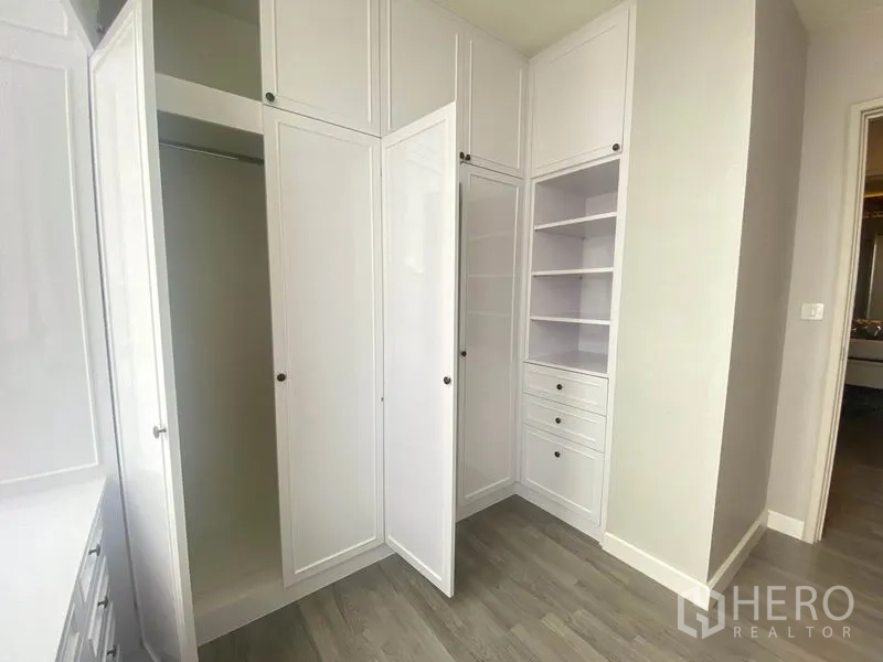 Condominium for rent in Bang Rak, Bangkok - Wall of white wardrobes and shelving providing ample storage space.