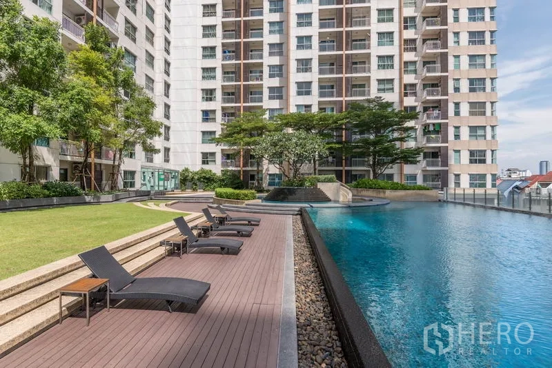 Condominium for rent in Bang Na, Bangkok - Condominium outdoor swimming pool with sun deck loungers and landscaped garden.