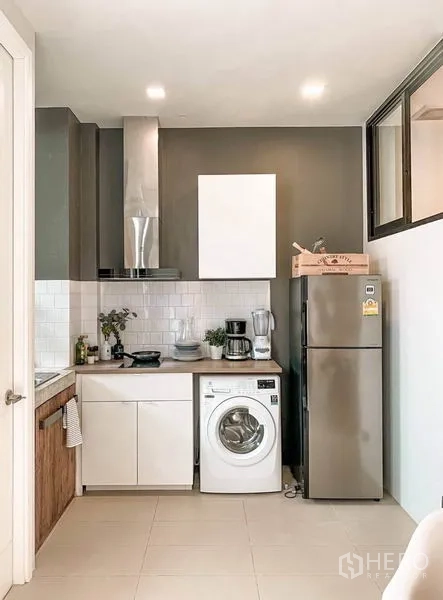 Townhouse for rent in Huai Khwang, Bangkok - Compact kitchen with subway tiles, range hood, refrigerator and washing machine.