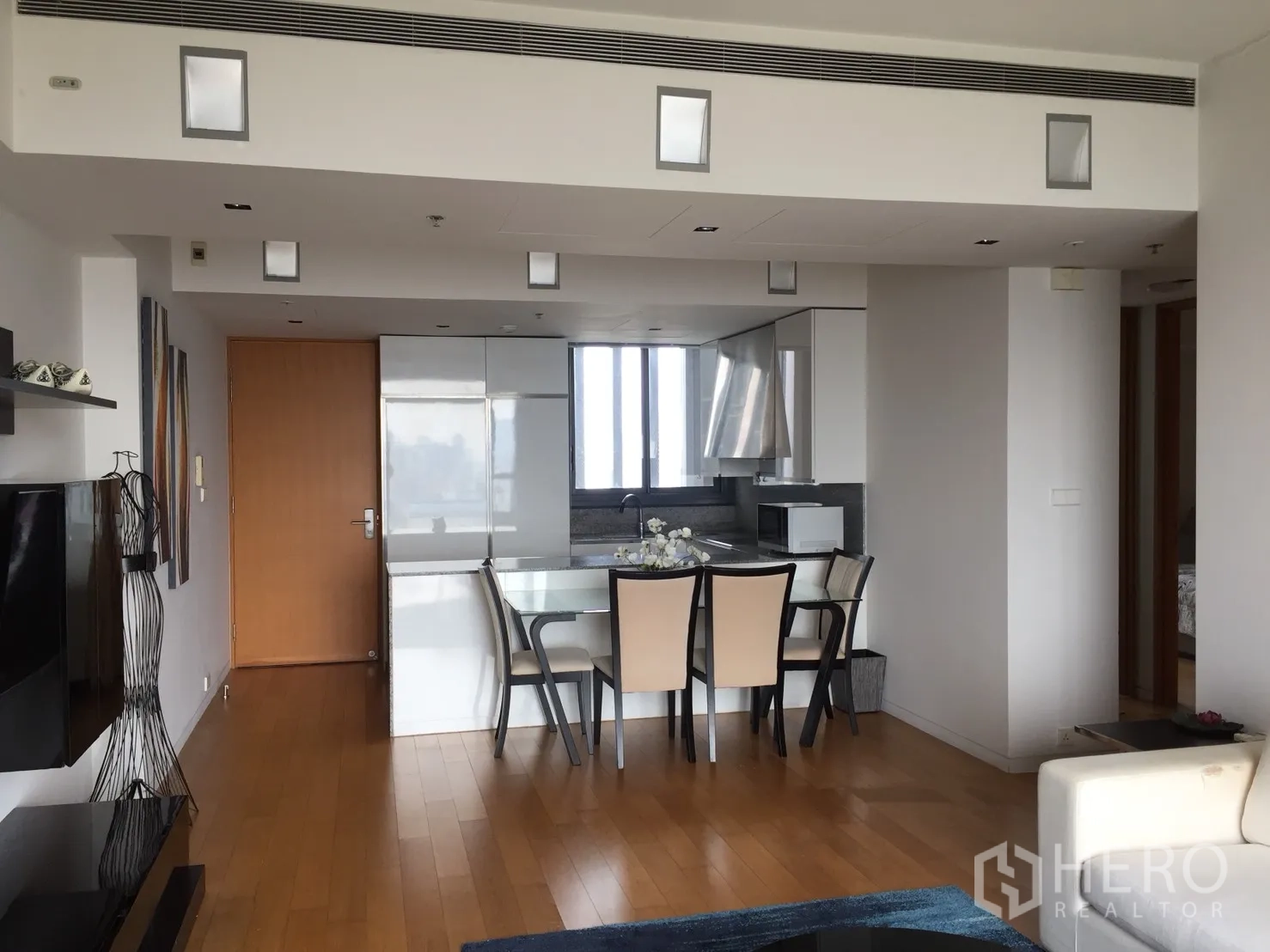 Condominium for rent or sale in Sathon, Bangkok - Open-plan living and dining area with hardwood floors and built-in storage.