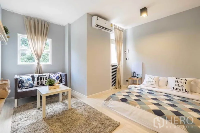 Detached House for rent in Khlong Toei, Bangkok - Light gray bedroom with low platform bed, window-side sofa and shaggy rug.