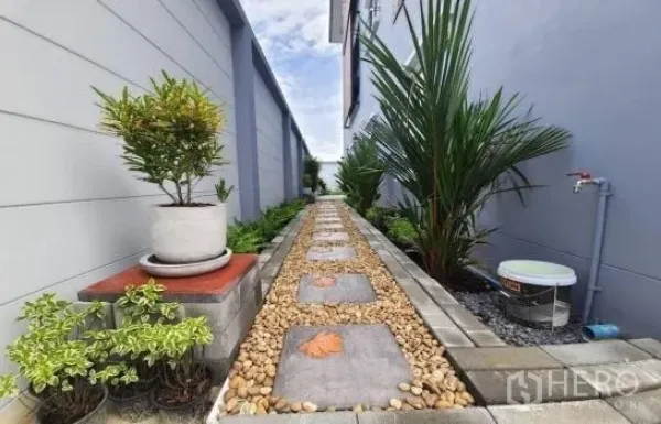 Townhouse for rent or sale in Saphan Sung, Bangkok - Landscaped side walkway with stepping stones, pebbles and potted plants at a Saphan Sung townhouse.