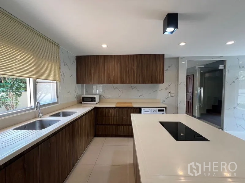 独立式住宅 出售在Mueang Pathum Thani, Pathum Thani - 厨房台面配双水槽、木质柜体与百叶窗。