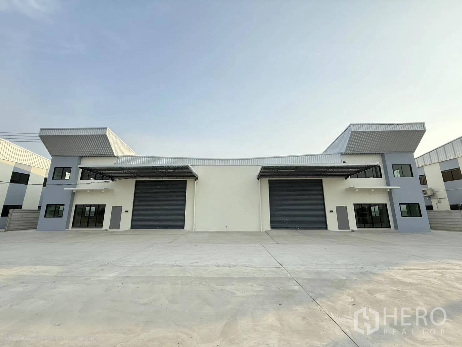 Factory for rent in Bang Phli, Samut Prakan - Modern standalone warehouse facade with two large roller shutter doors and a wide concrete yard in Bang Phli.
