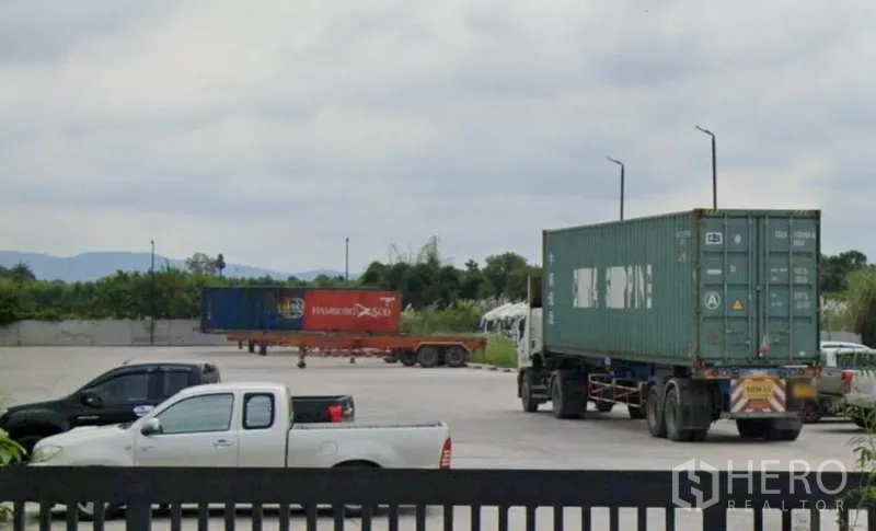 Warehouse for rent in Si Racha, Chon Buri - Wide concrete yard with container trucks and trailers at an industrial warehouse site in Si Racha, Chon Buri.
