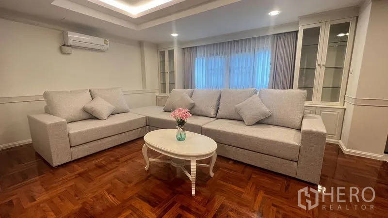 公寓 出租在Watthana, Bangkok - 客厅另一视角，圆形茶几、嵌灯与木质地板
