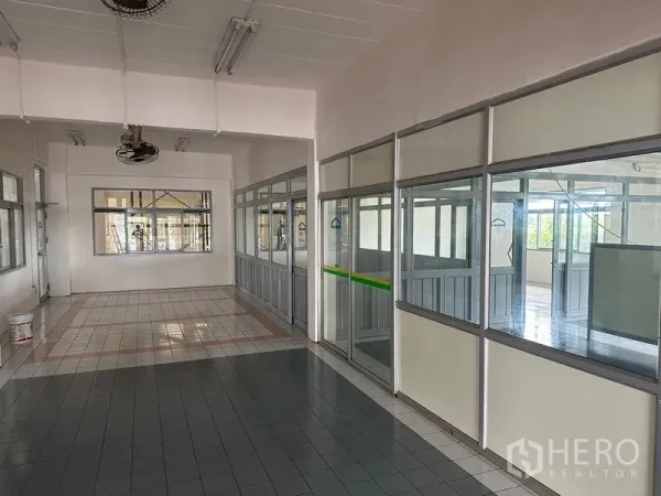 工厂 出租在Lam Luk Ka, Pathum Thani - 厂内走廊，玻璃隔断办公室与瓷砖地面。