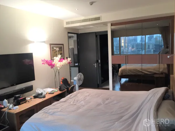 公寓 出售在Pathum Wan, Bangkok - 主卧配壁挂电视与镜面衣柜，映出城市景色。