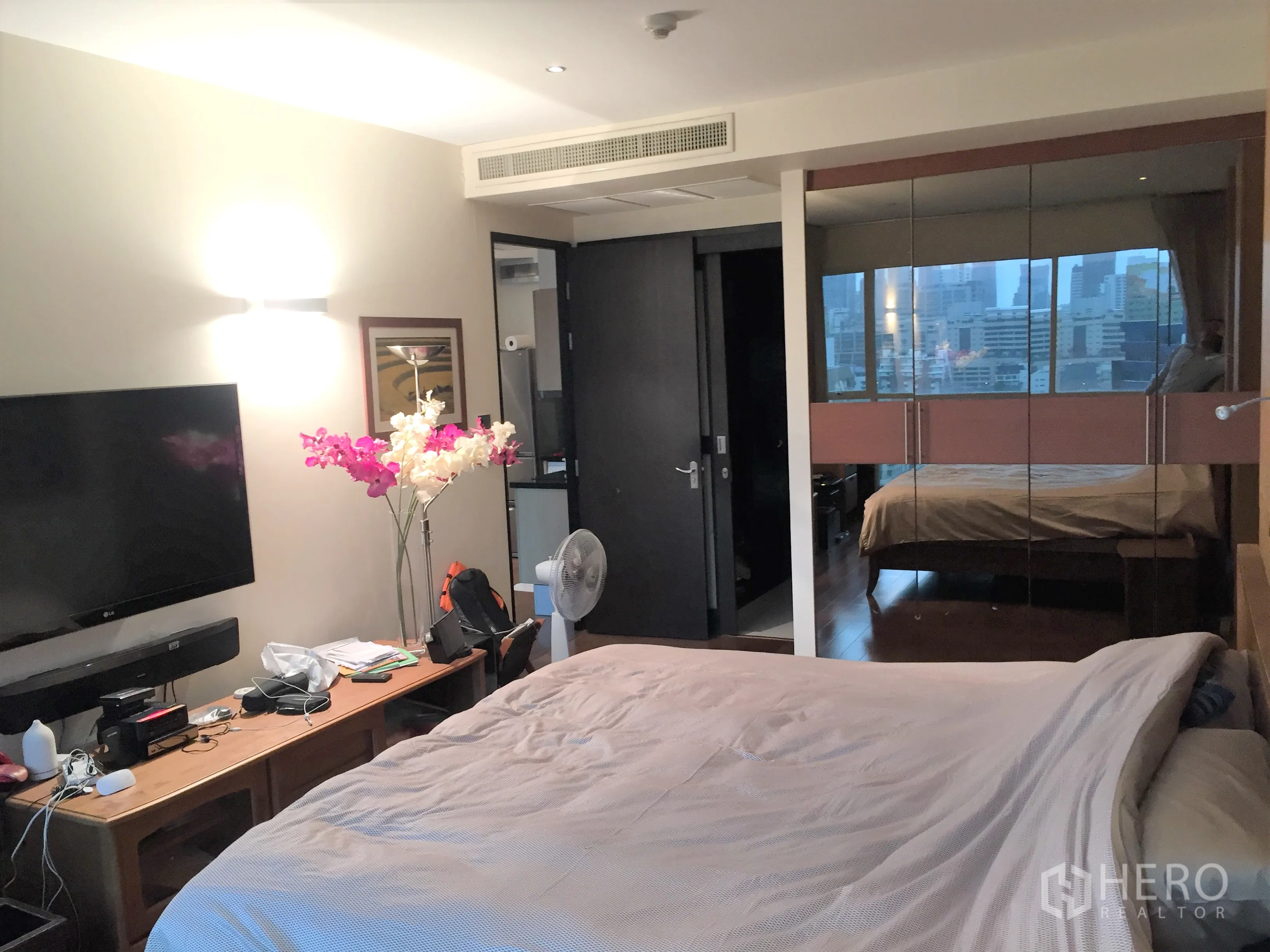 公寓 出售在Pathum Wan, Bangkok - 主卧配壁挂电视与镜面衣柜，映出城市景色。