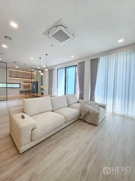 Detached House for rent - Living room with large cream sofa, sheer curtains and cassette air‑conditioning.