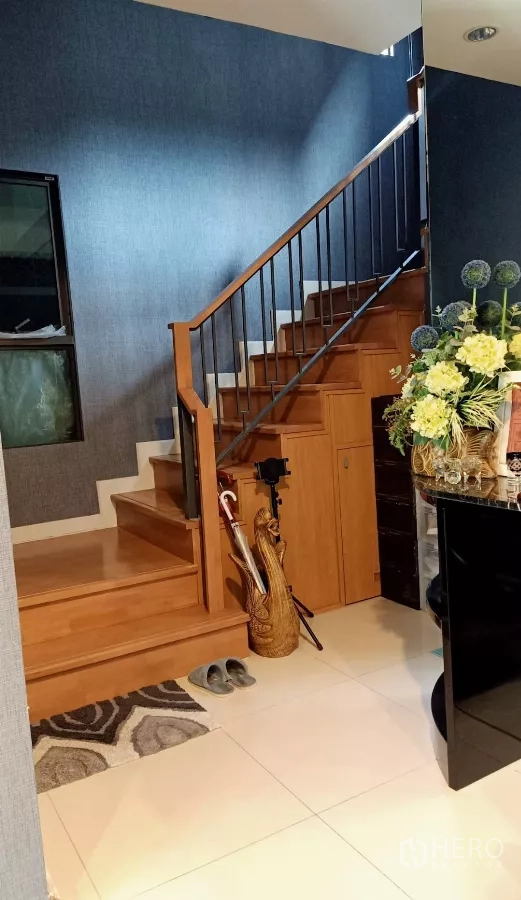 Detached House for rent or sale in Khan Na Yao, Bangkok - Entry hall with wood stairs, storage under stairs and decorative flower arrangement.