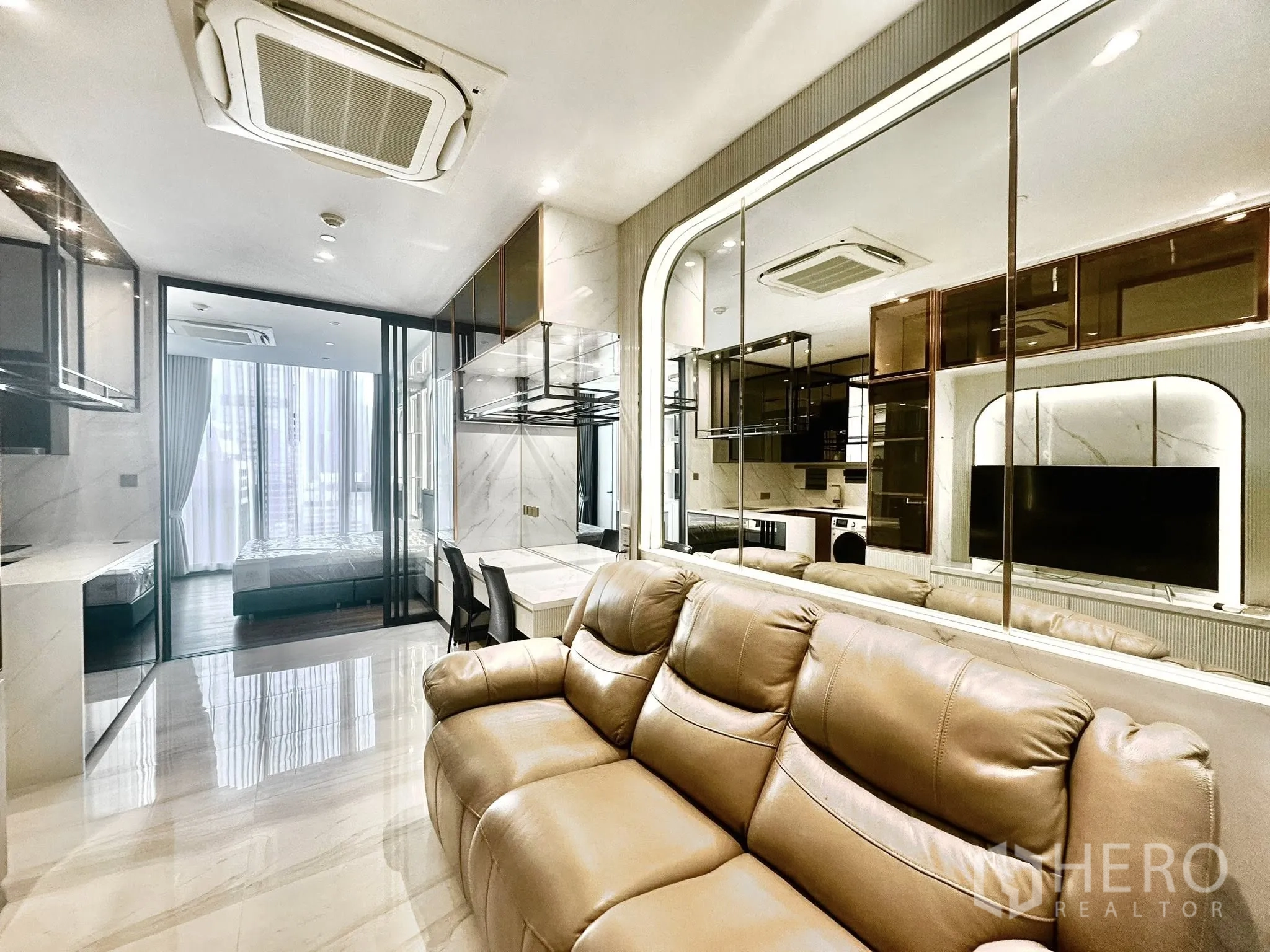 公寓 for rent in Sathon, Bangkok - 起居区配真皮电动沙发，面向镜面墙与开放式厨房。