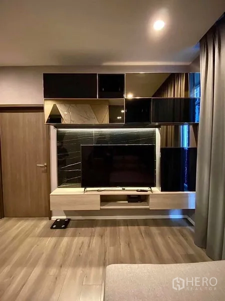 Condominium for rent in Phra Khanong, Bangkok - Modern living room TV console with glossy cabinets and wood flooring.