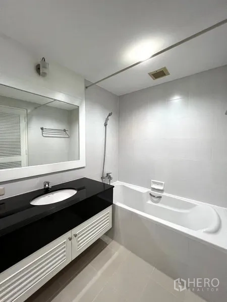 公寓 出租在Watthana, Bangkok - 现代浴室，带浴缸与淋浴，宽大镜面及黑色台盆柜。