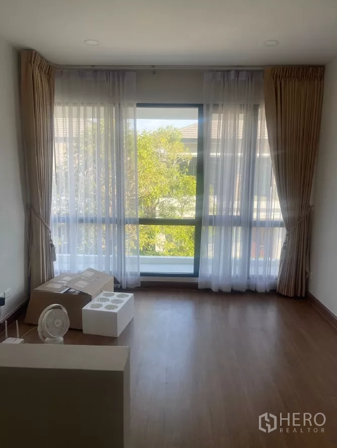 Detached House for rent or sale in Saphan Sung, Bangkok - Upstairs multipurpose room with floor-to-ceiling window and sheer curtains.