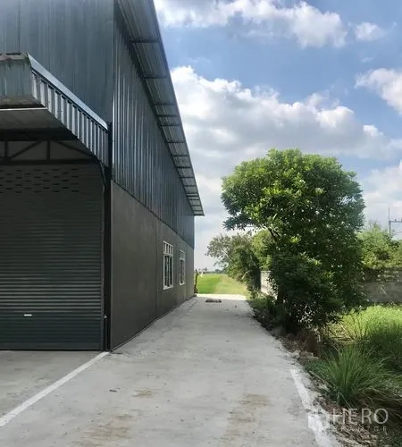 货栈 出租在Lam Luk Ka, Pathum Thani - 仓库侧后方带卷帘门与长通道。