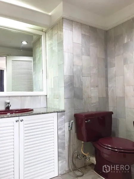 Condominium for rent or sale in Watthana, Bangkok - Bathroom with grey tiled walls, granite vanity, white louver cabinet and maroon toilet.