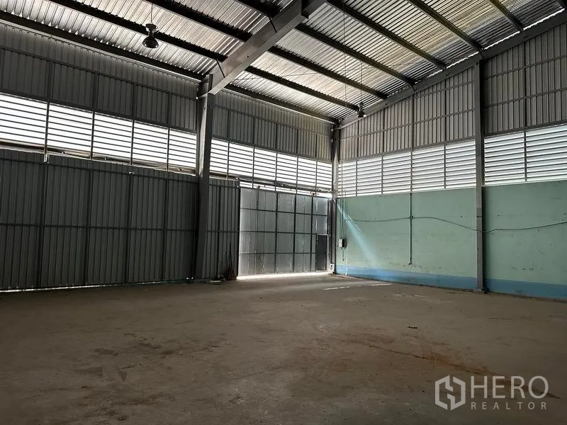 Warehouse for rent in Lam Luk Ka, Pathum Thani - Corner of warehouse with louvered windows, power points, and tall access gate.