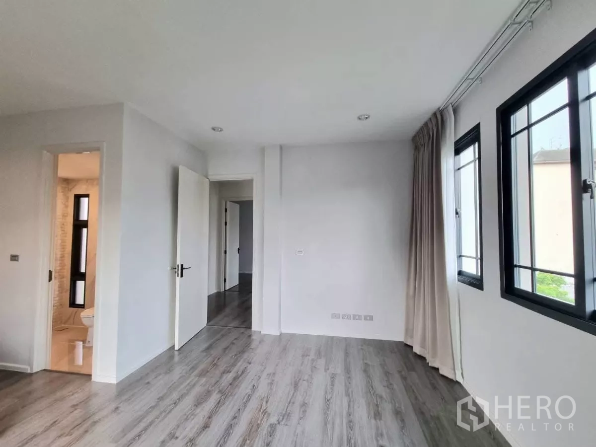 独立式住宅 出售在Prawet, Bangkok - 卧室过道，通往套内卫浴，多扇窗户。