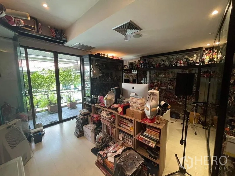 Townhouse for sale - Home office and hobby room with glass display cabinets and sliding doors to a leafy balcony.