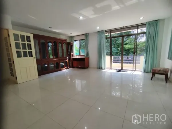 Detached House for rent in Watthana, Bangkok - Bright living room with glossy tiles, large windows, and balcony access.