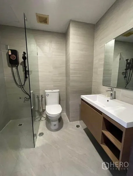 Condominium for rent - Bathroom with walk-in shower, vanity and toilet in grey tiling.