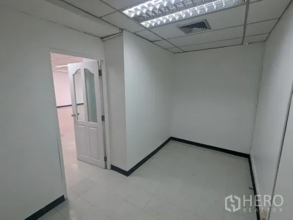 สำนักงาน ให้เช่าหรือขาย - ห้องทำงานส่วนตัวขนาดกะทัดรัด ผนังสีขาว พื้นกระเบื้อง และประตูกระจกใต้ไฟฟลูออเรสเซนต์