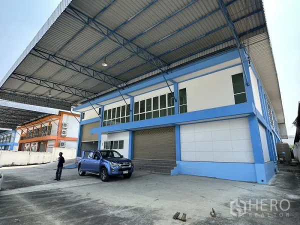 Factory for rent in Bang Bo, Samut Prakan - Front facade of factory featuring a covered loading dock, glass-panel office windows and a large roller door.