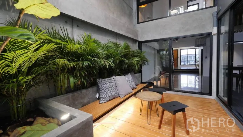 联排别墅 出租在Khlong Toei, Bangkok - 庭院休闲区，内置花槽、热带植栽与木长凳。