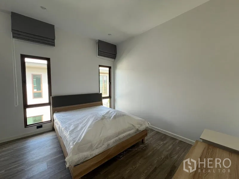 Detached House for rent in Bang Kapi, Bangkok - Guest bedroom with minimalist décor, bed and twin narrow windows.