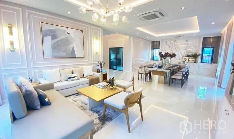 Detached House for sale in Bang Phli, Samut Prakan - Bright open‑plan living and dining room with chandelier, wall moulding and sleek kitchen access in a Bang Phli detached house