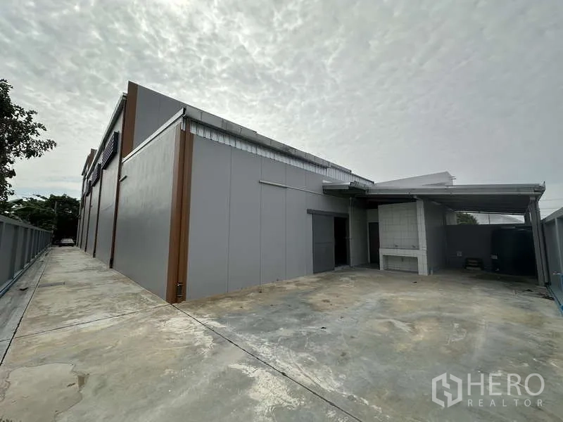 Factory for rent or sale in Bang Bua Thong, Nonthaburi - Rear exterior service yard with partial roof cover and side driveway.