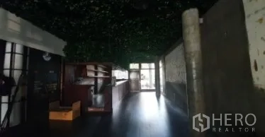 零售空间 出租在Khlong Toei, Bangkok - 昏暗的店内空间，设吧台、深色地板与绿植天花装饰。