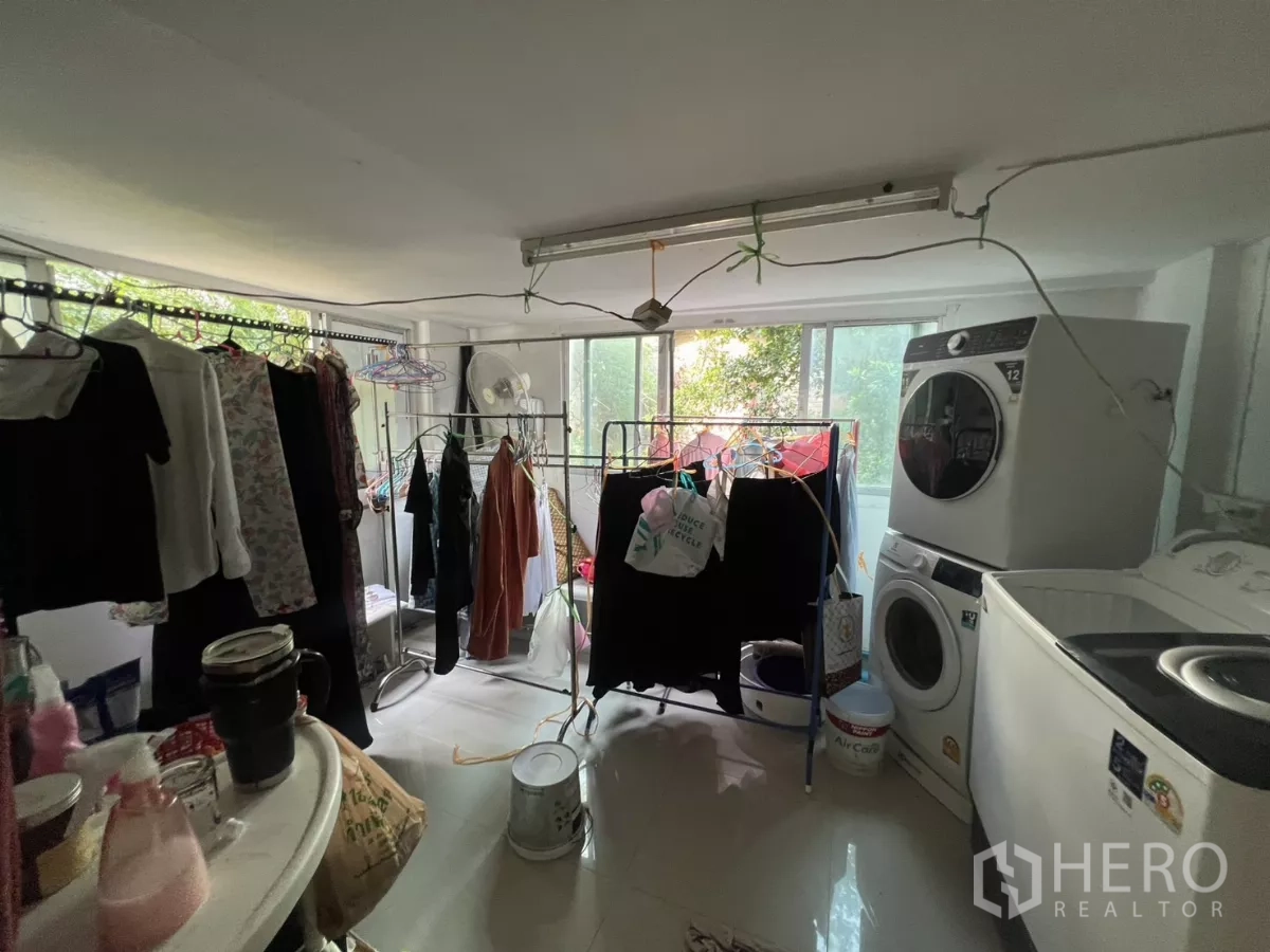 Retail Space for rent - Utility room with washing machines, clothing racks, and large windows providing natural light.