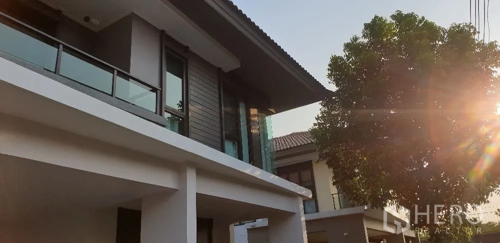 Detached House for rent or sale in Lam Luk Ka, Pathum Thani - Close-up of upper facade with glass railing and afternoon sunlight.