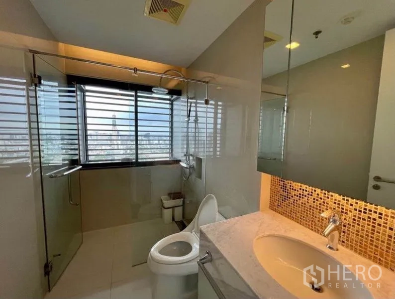 Condominium for sale in Ratchathewi, Bangkok - Second bathroom with walk-in glass shower and mosaic-tile vanity.