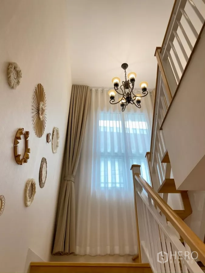 Detached House for sale in Sai Mai, Bangkok - Staircase landing with chandelier and tall draped window.