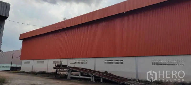 货栈 出租在Nikhom Phatthana, Rayong - 橙色金属外墙仓库外观，带装卸坡道和作业场地，位于罗勇尼空帕塔那。