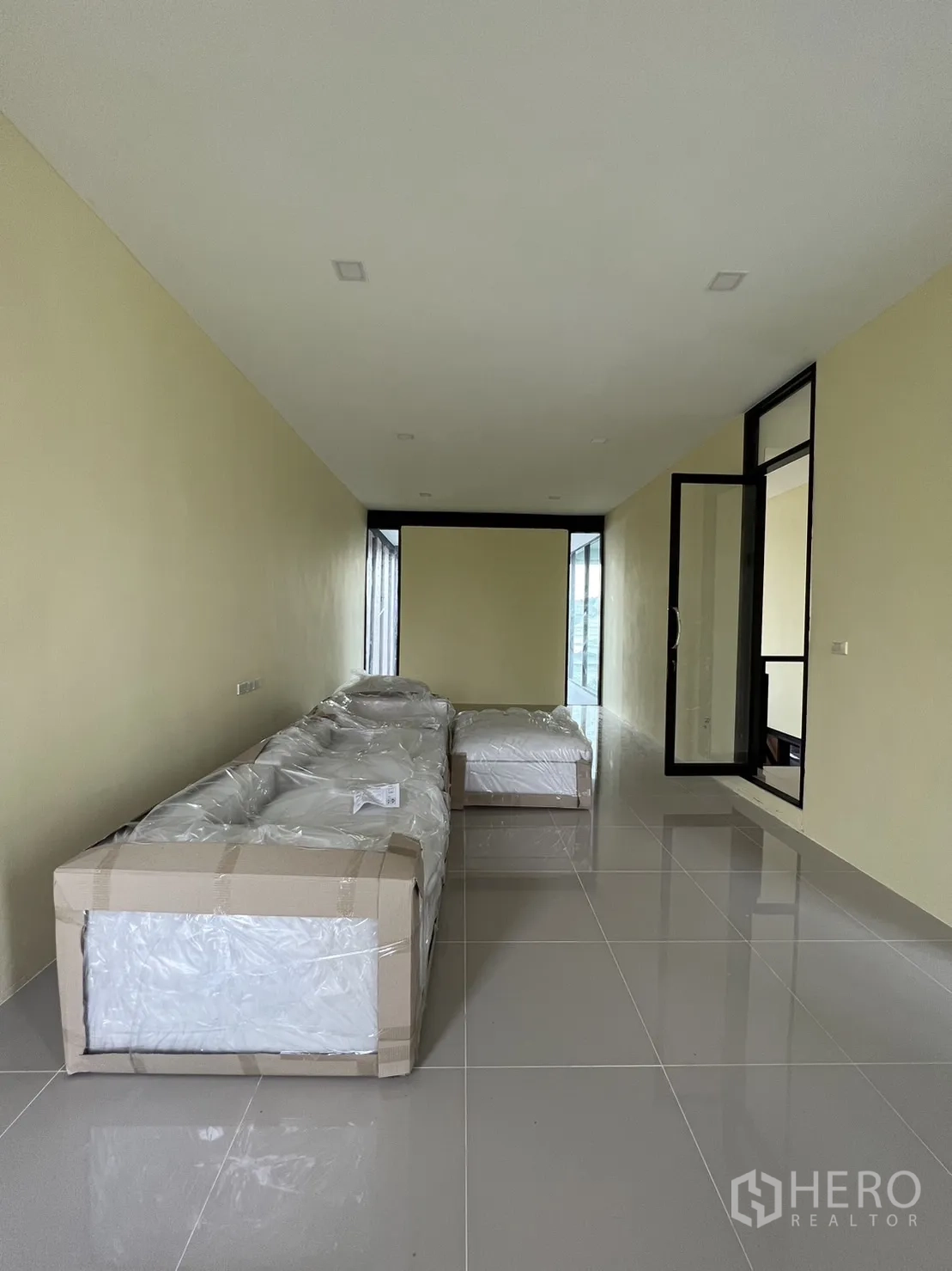 Detached House for rent or sale in Phra Khanong, Bangkok - Long upstairs multipurpose room with packaged furniture on glossy tiles.