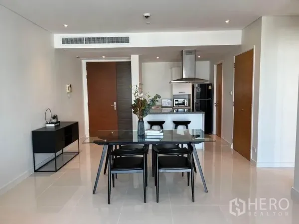 Condominium for rent in Watthana, Bangkok - Dining area and kitchen with glass table and white cabinetry in bright condo.
