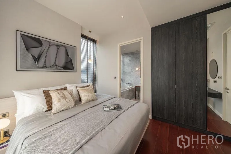 Condominium for rent in Watthana, Bangkok - Cozy bedroom with large dark wardrobe and doorway to an ensuite bathroom.