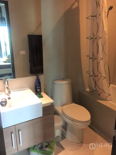 公寓 出租或出售在Watthana, Bangkok - 浴室配现代洗手台、坐便器与浴缸淋浴组合。