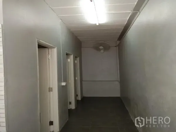 货栈 出租在Bang Phli, Samut Prakan - 通往员工卫生间与功能房的走廊，灰色墙面与顶灯