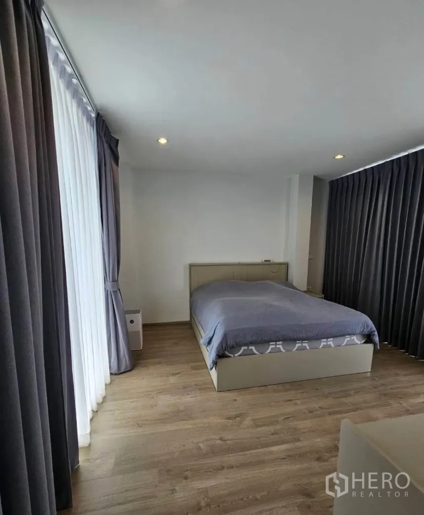 Detached House for rent or sale in Lat Krabang, Bangkok - Corner bedroom with panoramic windows, wood floors and grey curtains