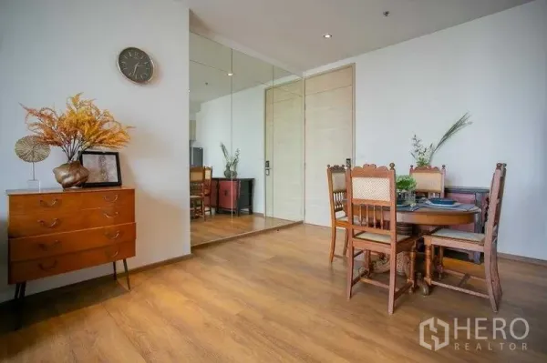 Condominium for sale in Khlong Toei, Bangkok - Corner with wooden sideboard and round dining table on warm wood flooring.