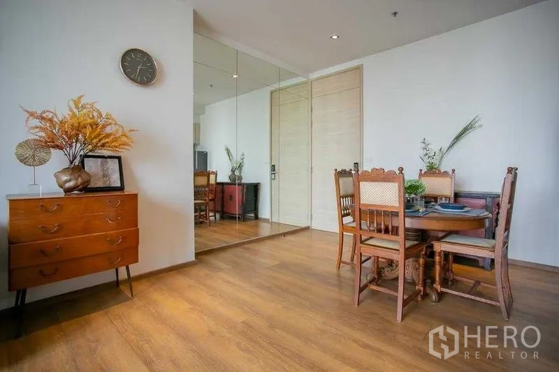 Condominium for sale in Khlong Toei, Bangkok - Corner with wooden sideboard and round dining table on warm wood flooring.