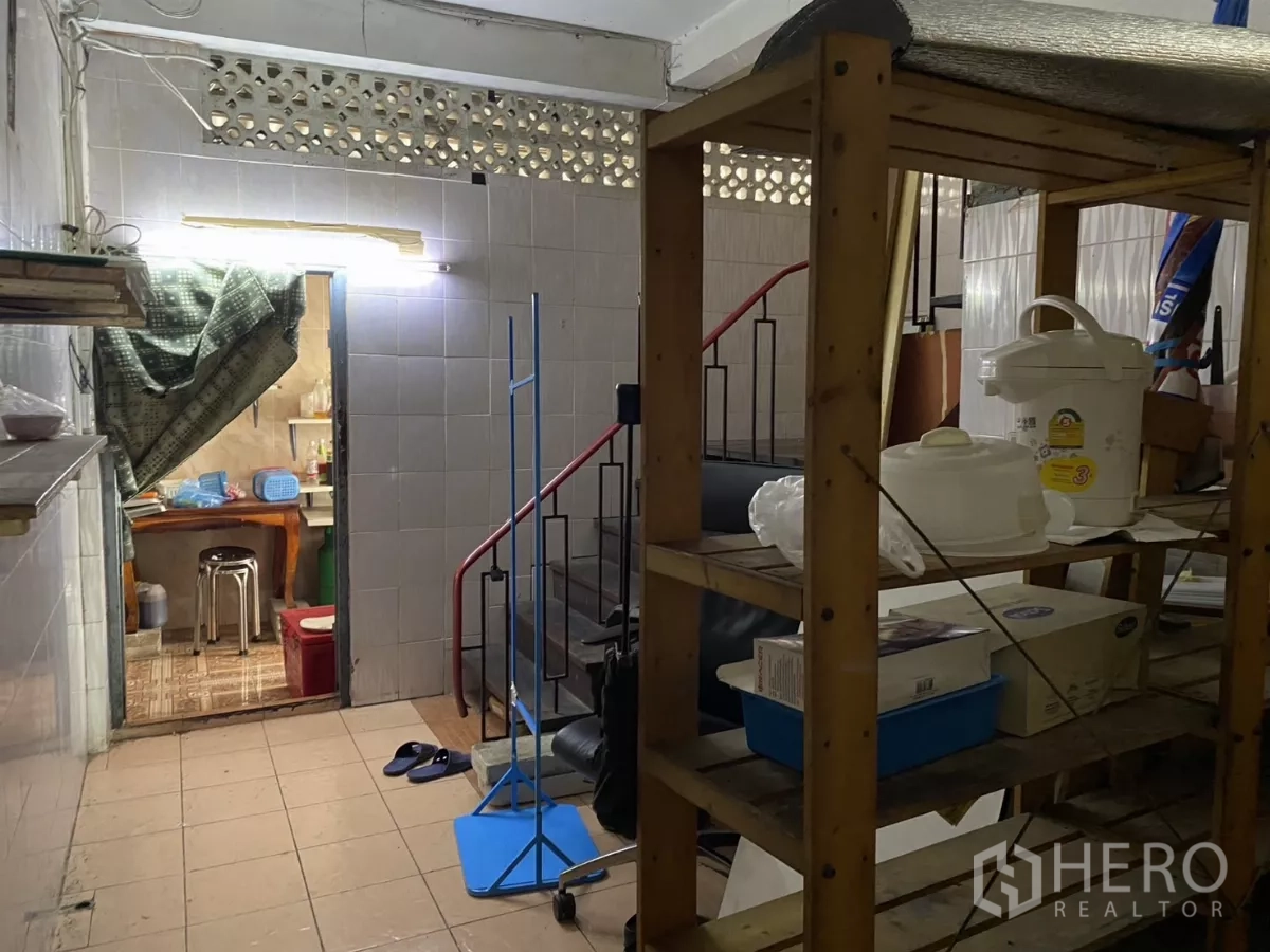 Shophouse for rent in Khlong Toei, Bangkok - Utility area with wooden shelving and staircase beside tiled walls.